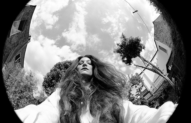 A black-and-white self-portrait of a woman taken with a fisheye lens